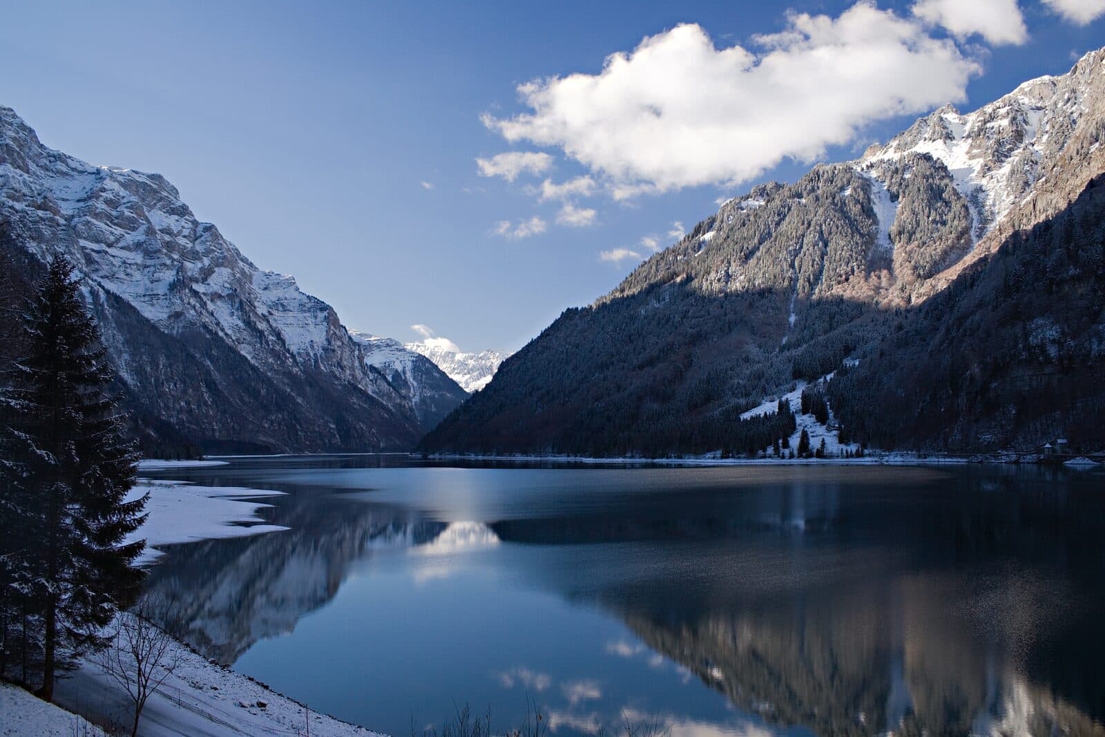 Lake Klöntal between steep mountains dusted with snow
