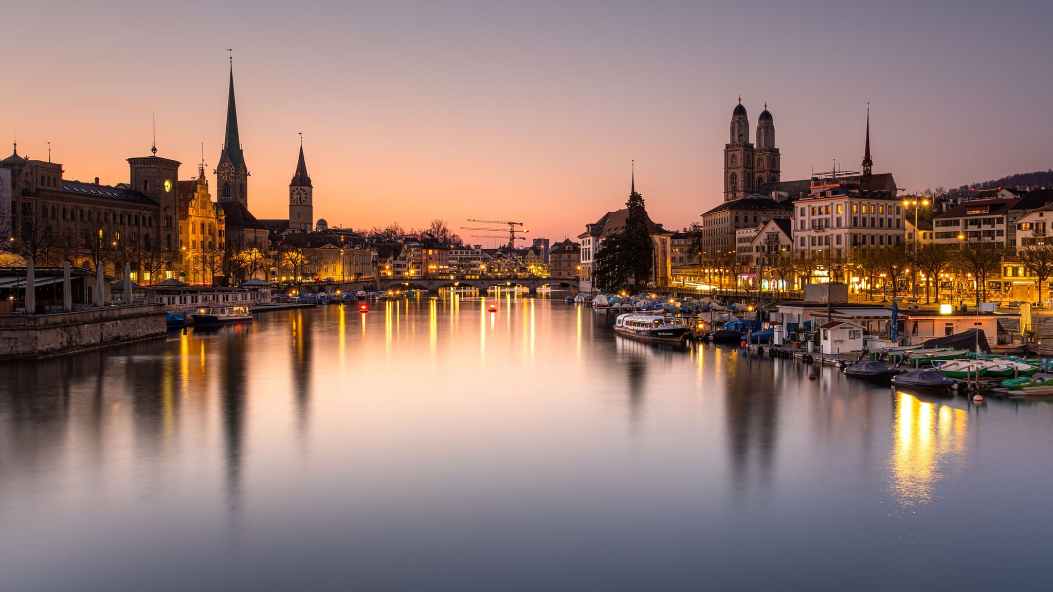 Città vecchia di Zurigo e la Limmat al tramonto, con le torri del Grossmünster, del Fraumünster e di San Pietro.